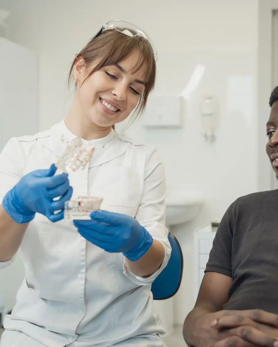 Dentist showing a dental model to a smiling patient