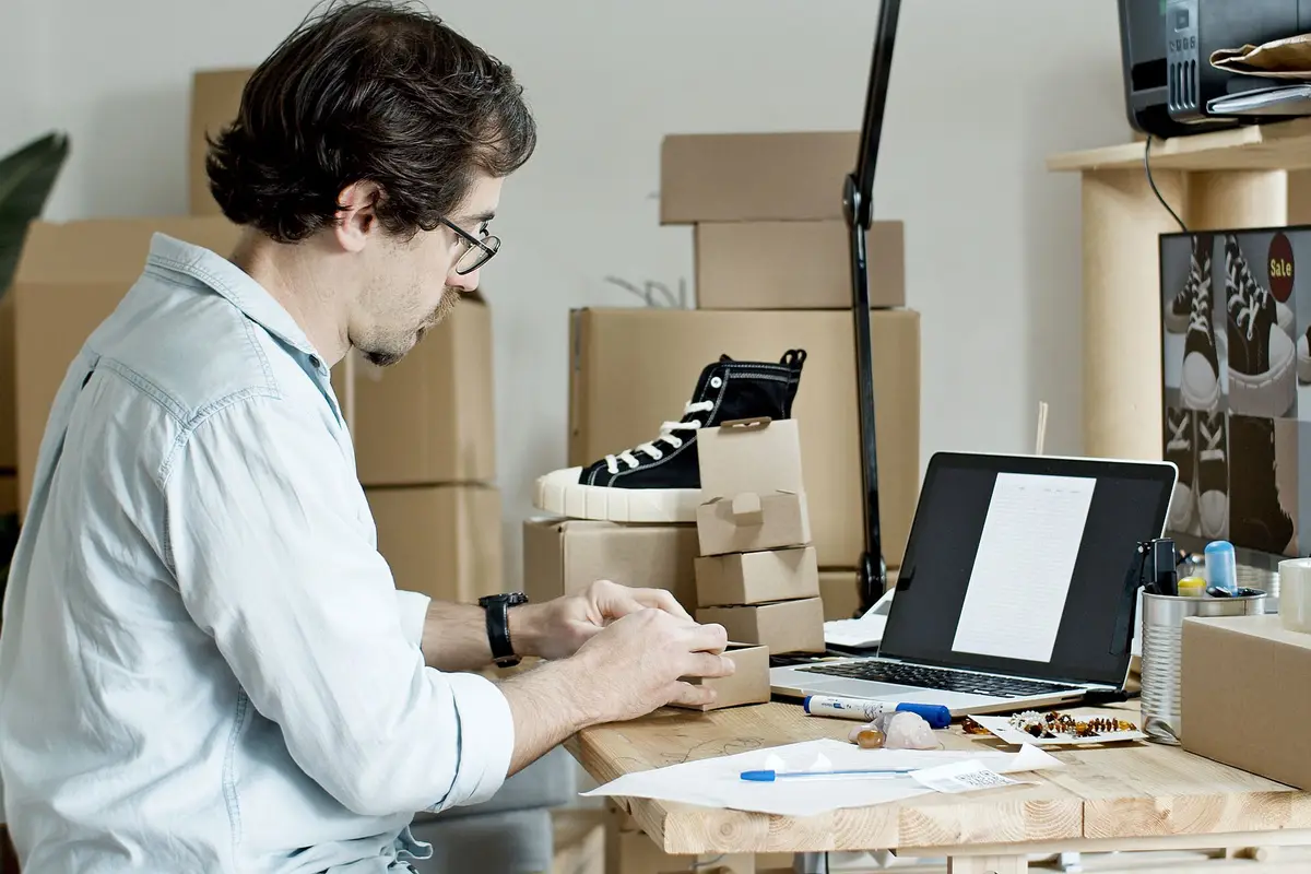 Store owner preparing parcels at a desk with a laptop