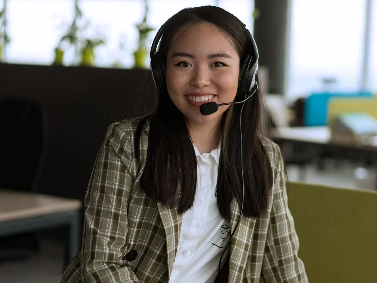 Support agent smiling at her desk wearing a headset