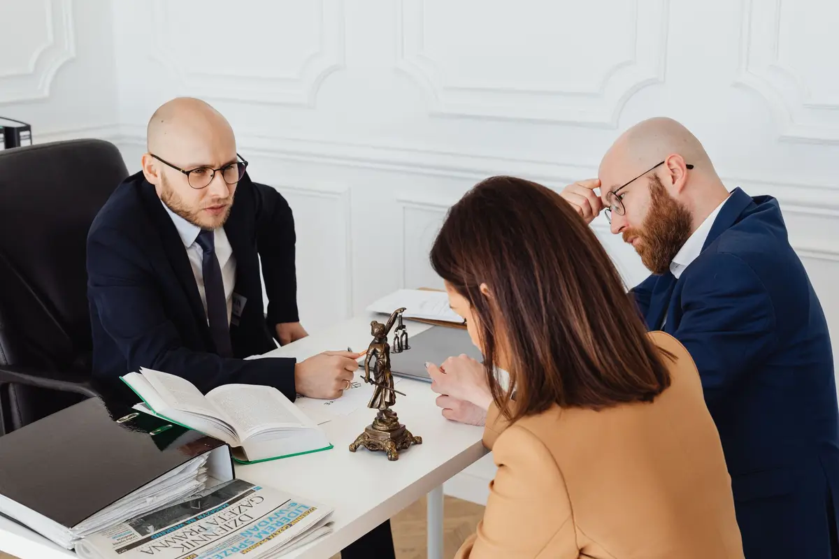 Lawyers meeting a client across a desk with documents