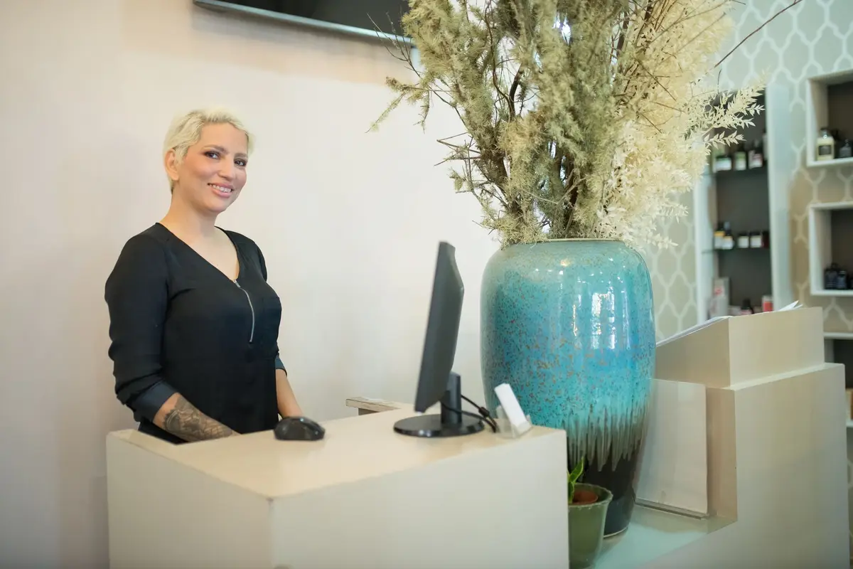 Receptionist smiling behind the front desk of a bright studio
