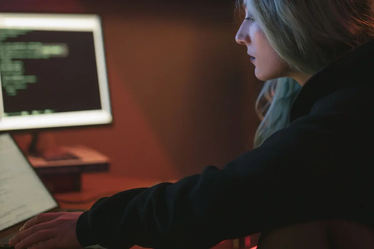 Developer working late at a laptop with code on a second monitor
