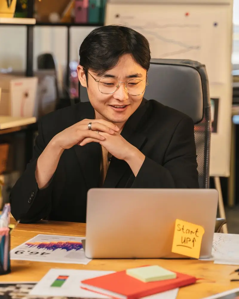 Smiling man at a laptop in a bright office