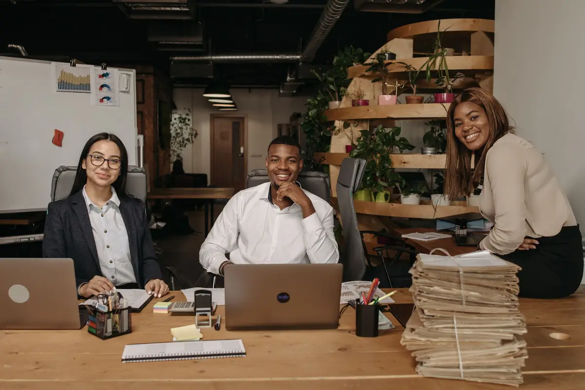 Sales team smiling at their desks in a busy office